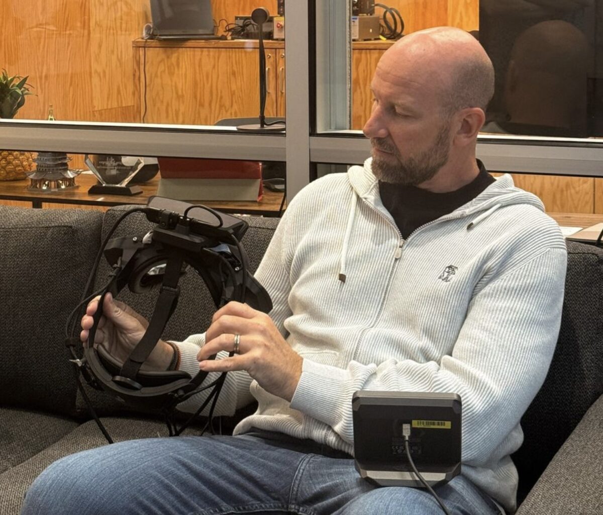 Bosworth sits on a bed and stares at a virtual reality TV screen.